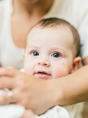 Baby's face in focus, parent's arms blurred