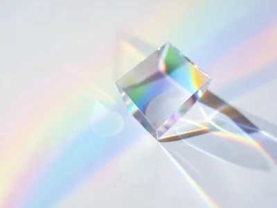 Soft prismatic light fanning across a matte white surface, gentle pastel rainbow