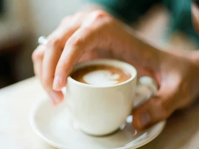 Hand reaching for coffee cup, background dissolved