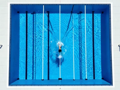 An Olympic-length swimming pool viewed from directly above, eight white lane lin