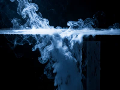 Dry ice fog cascading off a table edge like a waterfall, moody blue lighting