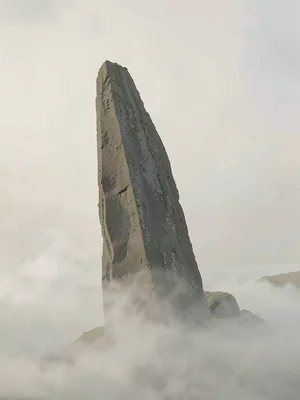 Towering menhir leaning slightly, base wreathed in fog, no other landmark anywhe