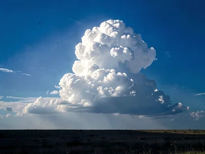 Single towering cumulus alone in otherwise empty blue field
