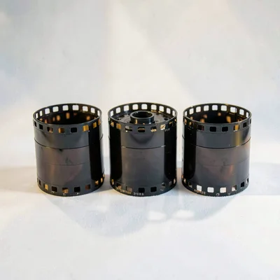 Studio composition of three film rolls arranged in a tidy row on a soft white sw