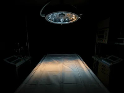 Overhead surgical lamp pooling cold light on an empty operating table draped in 