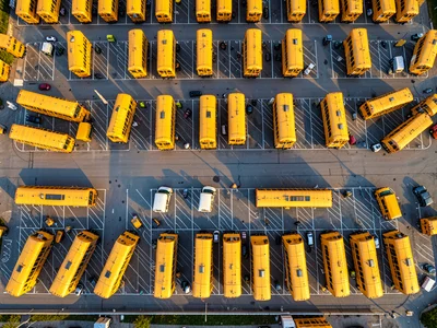 A parking lot filled with yellow school buses arranged in rows, the pattern like