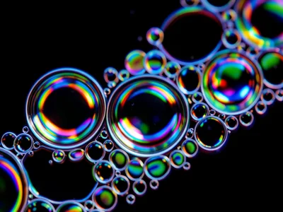 Minimal oil on water, just three large floating lenses on deep black background,