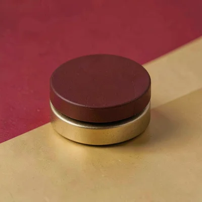 Block-color of a stack of two flat round caps, oxblood and antique gold palette
