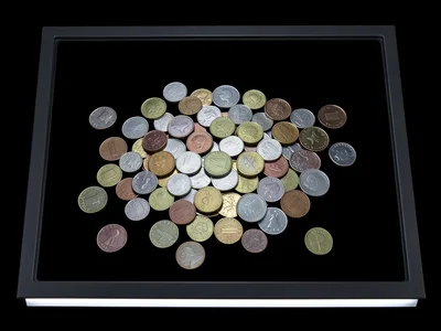 Pile of assorted coins from different countries spread across scanner glass, var