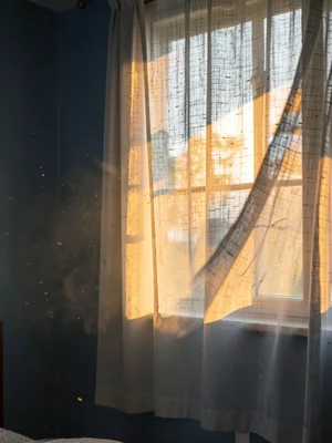 Curtain in slow morning breeze with amber shaft
