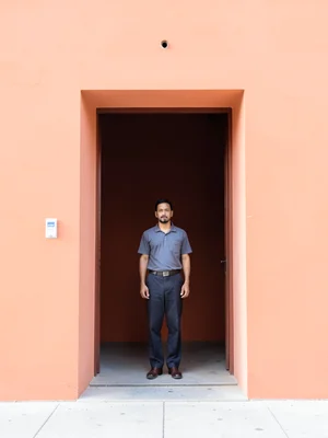 Perfectly centered doorway in salmon-colored wall, figure standing in center