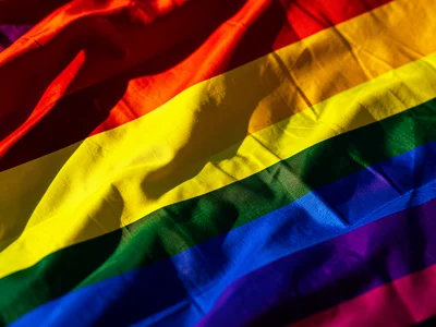 Close-up of rainbow flag fabric rippling in wind, saturated colors