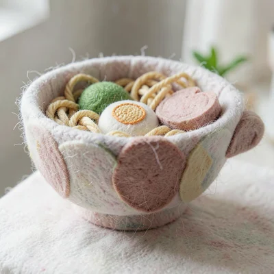 Cross-section of a knit ramen bowl revealing yarn noodles, embroidered egg, and 