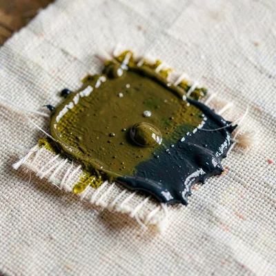 Surface macro of a linen canvas patch loaded with wet oil pigment