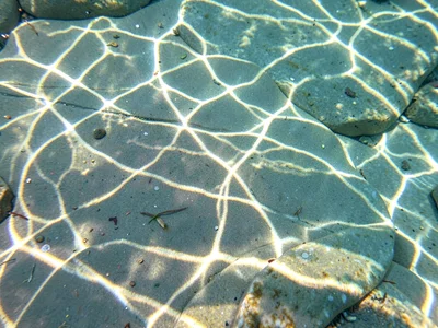 Shadow of surface ripples playing across smooth stone bottom
