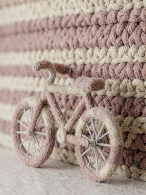 Bicycle in felted wool leaning against a knit wall of horizontal stripes in oatm