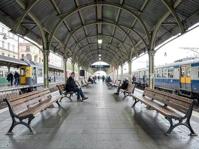 Person waiting at empty train platform, benches stretching both directions, the 