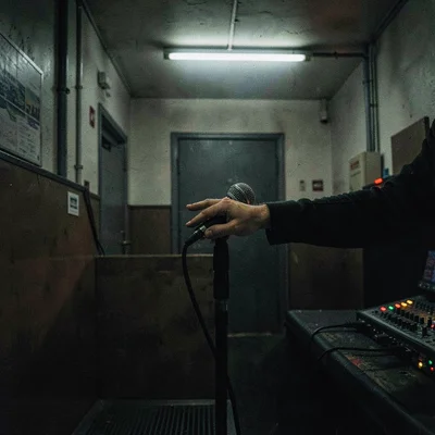 After-hours scene of a singer's hand reaching for a microphone in a dimly lit bo