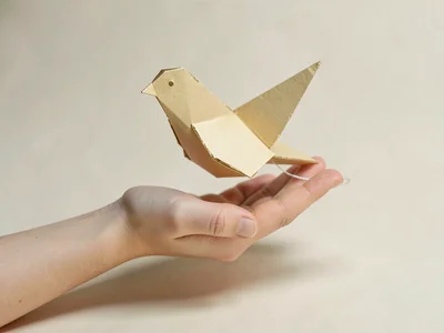 A wide soft-papercraft hand offering a folded paper bird with no string attached
