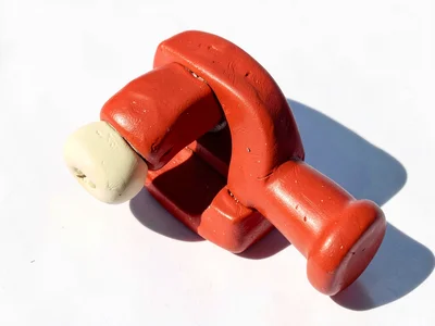 Hardworking chunky clay vise in cherry red with stubby cream-toned jaws and over