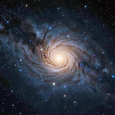 A barred spiral galaxy viewed nearly face-on with a bright central bar and two m