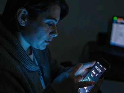 Person receiving "sorry for your loss" texts, phone screen lighting grief, the m