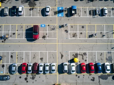 A shopping mall parking lot at 10am on a Saturday from 200 feet above, roughly 6