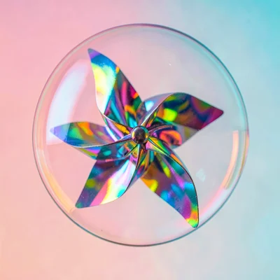Holographic foil pinwheel caught mid-spin in tight macro against a sunrise pink-