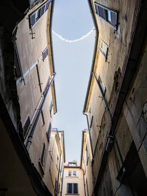 Looking straight up in a narrow alley between buildings, walls curving inward li