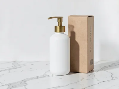White matte bottle with brass pump on marble