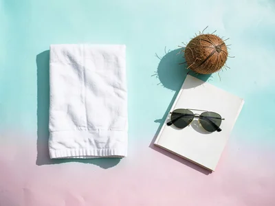 Symmetrical flat-lay of beach essentials a folded linen towel a coconut a paperb