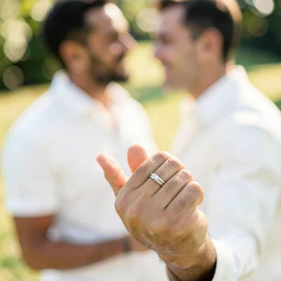 Engagement ring on finger, couple beyond blurred