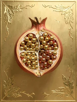 A single pomegranate split open, the seeds replaced with gold beads
