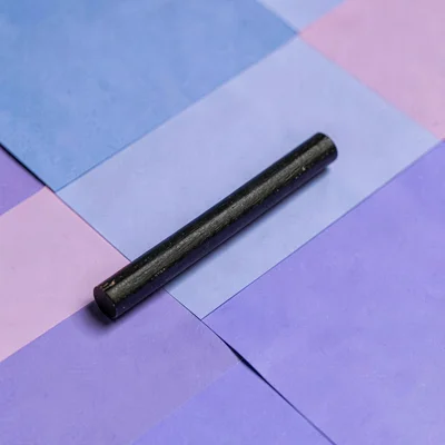 Catalog ad of a charcoal stick on a periwinkle block, hairline shadow