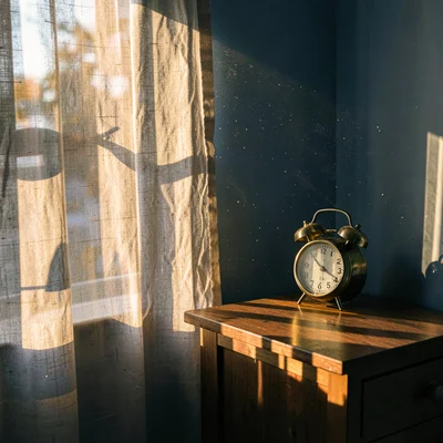 Brass clock on bedside table in morning shaft