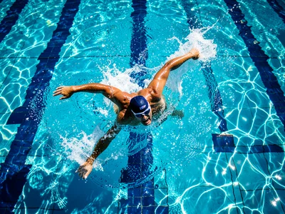Swimmer cutting through clear pool water, overhead view, perfect form, lane line