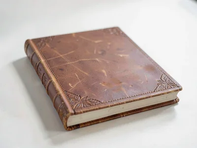 One leather-bound photo album lies flat showing embossed corner accents and a so