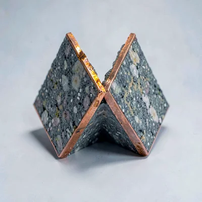 Two interlocking mineral wedges meeting at a sharp seam, oxidized copper rim, so