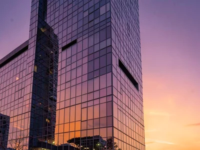 Glass tower reflecting sunset gradient orange to purple