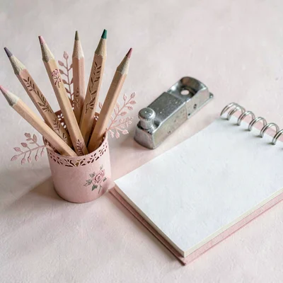 Papercraft still life of paper-cut pencils, sharpener and sketchpad in butter an