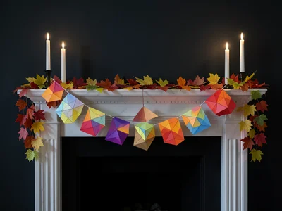Paper bat garland hung across mantelpiece, candles, autumn leaves arranged