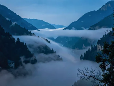 Fog waves spilling through mountain pass like water