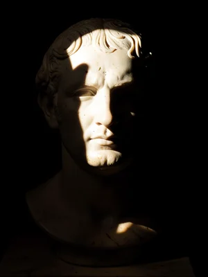 Hard side-light raking across a marble bust of an unknown emperor, half the face