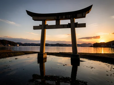 Traditional Japanese torii gate standing in shallow water at sunset