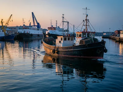 A lobster boat heading out at dawn, the bow cutting through calm water, traps st