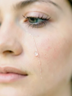 Single tear tracking down cheek in crystalline focus, entire face dissolved into