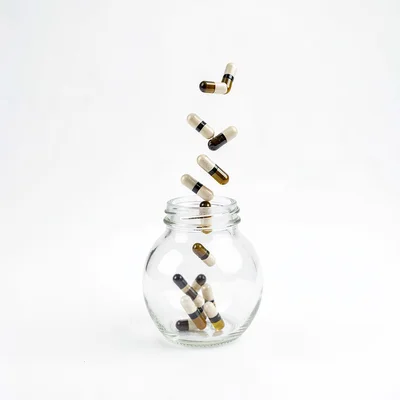 Minimal composition of capsules tumbling from a tilted bottle on white seamless