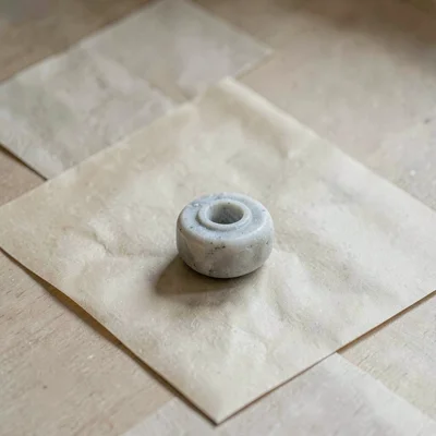 One small piece of carved soapstone in pale dove grey resting alone on washed be