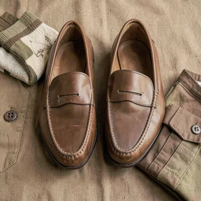Warm flatlay of leather loafers, folded socks and a folded shirt in earth tones