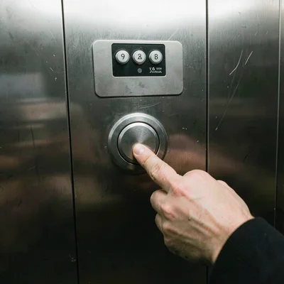 The close-door button being pressed by an impatient finger